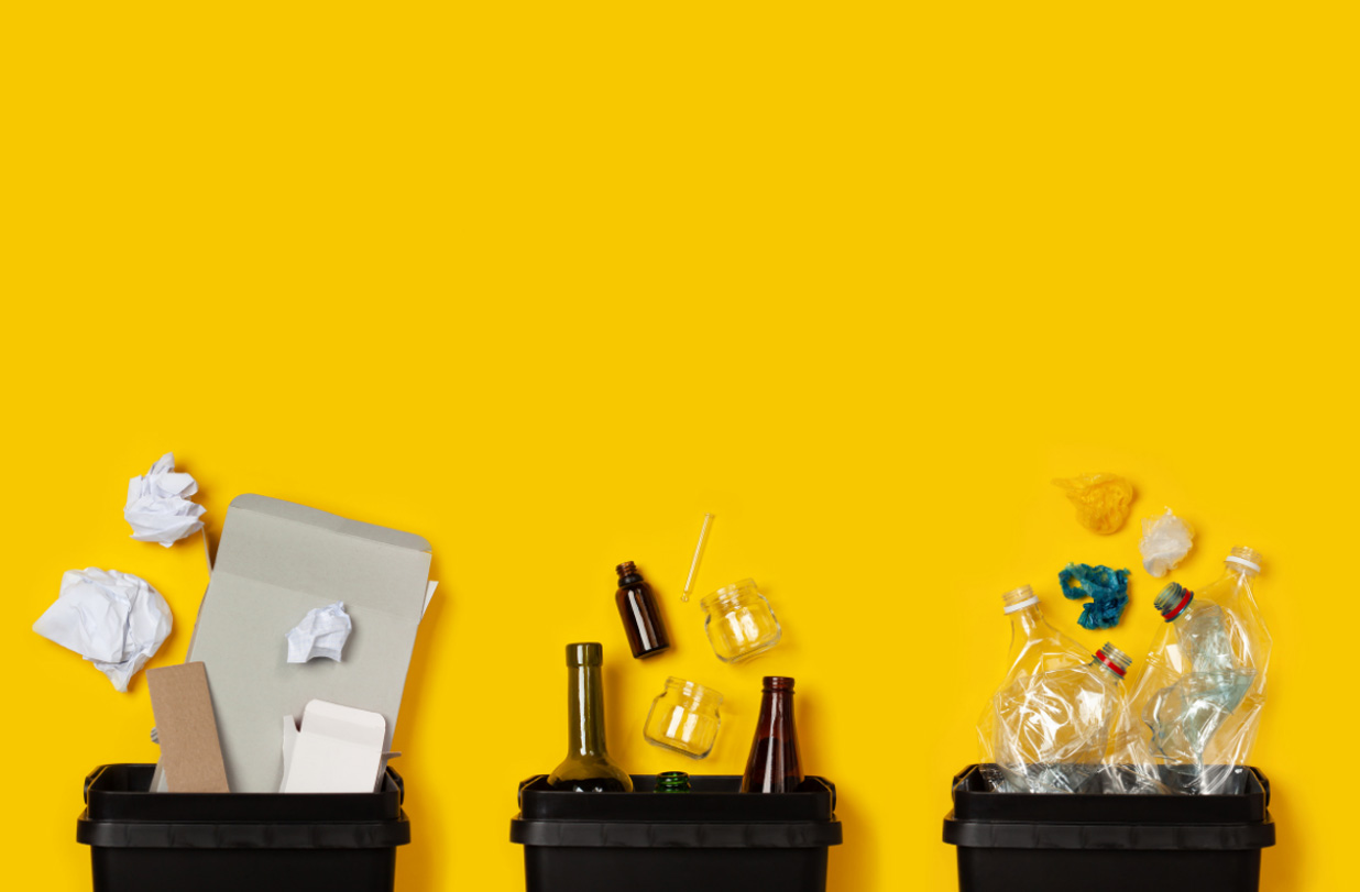 Drei Mülleimer vor gelbem Hintergrund
